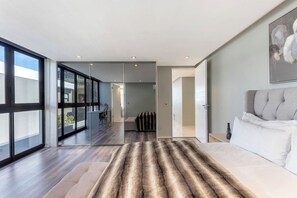 A modern hotel room with a large window, a fur rug, a bed, and a painting on the wall. - The Blouberg Lookout (Cape Town)