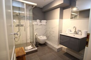 Ein modernes Badezimmer mit einer gläsernen Duschkabine, einer Toilette und einem Waschtisch.