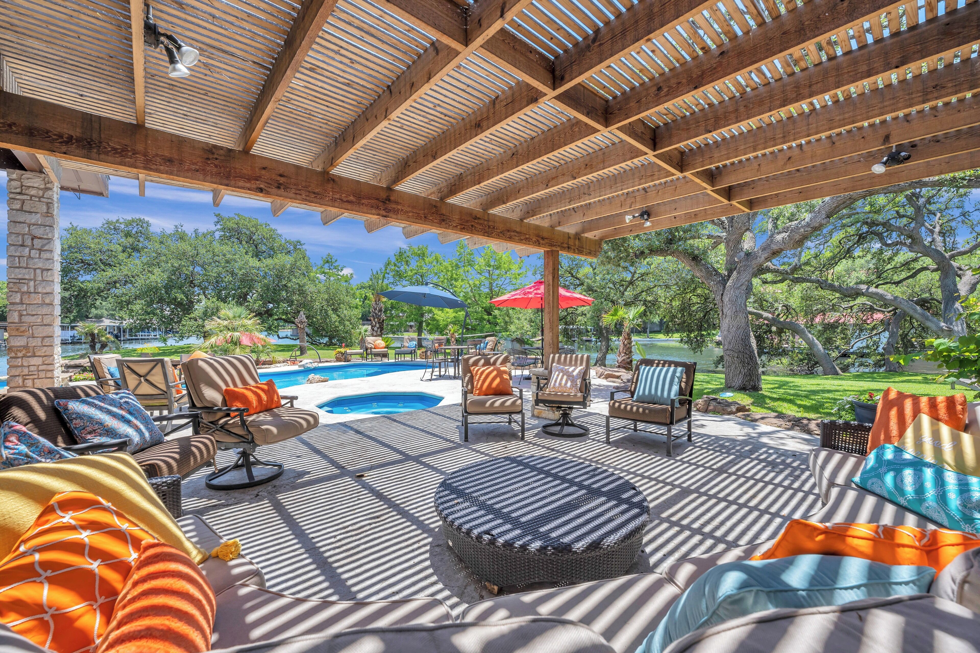 Eine Terrasss mit Pool, Liegestühlen und Sonnenschirmen.
