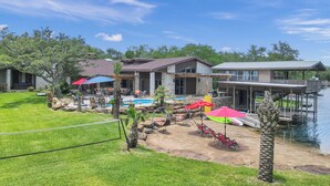 Ein Wohnhaus mit Schwimmbad, Terrassenmöbeln und einer Anlegestelle im Wasser.