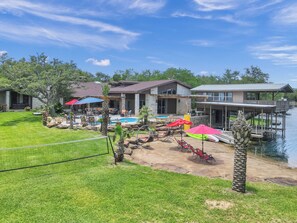 Ein Wohnhaus mit Schwimmbad, Terrassenmöbeln und einer Anlegestelle im Wasser.