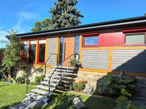A modern house with a red door, a staircase leading to the entrance, and a well-maintained garden. - An oasis of peace, where charm and elegance meet nature—a chalet in Western Lusatia (Haselbachtal)