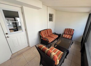A room with a white door, a small window, and two black wicker sofas with striped cushions. - Relaxing Naples Getaway close to the Beach (Naples)