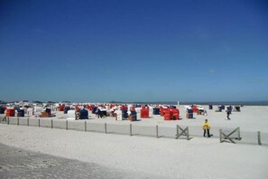 Een strand met tal van rode en witte tenten, een zandstrand en een heldere lucht.