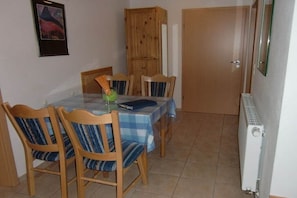 Een eethoek met een tafel bedekt met een blauw-witte geruite tafelkleed, omringd door houten stoelen met gestreepte kussens.