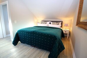 Un dormitorio con cama, mesitas de noche y espejo.