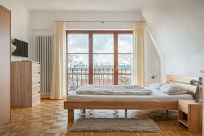 Ein Schlafzimmer mit großem Fenster, einem Bett, einem Nachttisch und einer Heizung.