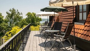 Un terrazzo in legno con posti a sedere all'aperto e ombrelloni, affacciato su una distesa d'acqua.