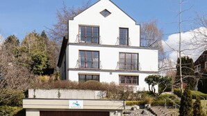 Un edificio di due piani con facciata bianca, numerose finestre e balconi.