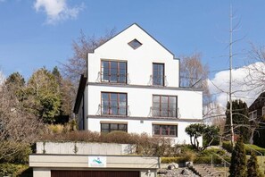 Ein zweigeschossiges Gebäude mit weißer Fassade, zahlreichen Fenstern und Balkonen.