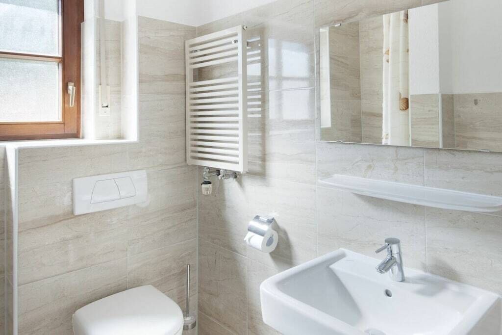 A bathroom with a toilet, a sink, a mirror, and a towel rack.