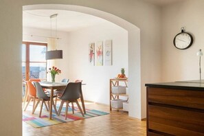 A modern kitchen with a dining area, wooden cabinets, a clock, and artwork on the wall. - La Perla - Sea Pearl (Überlingen)