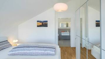 A modern bedroom with a bed, bedside table, and a view of a bathroom.