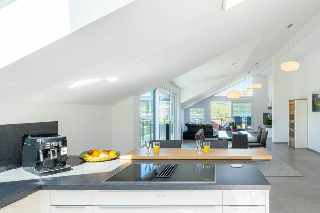 A modern kitchen with a built-in espresso machine, a fruit bowl, and a dining area with a table and chairs.