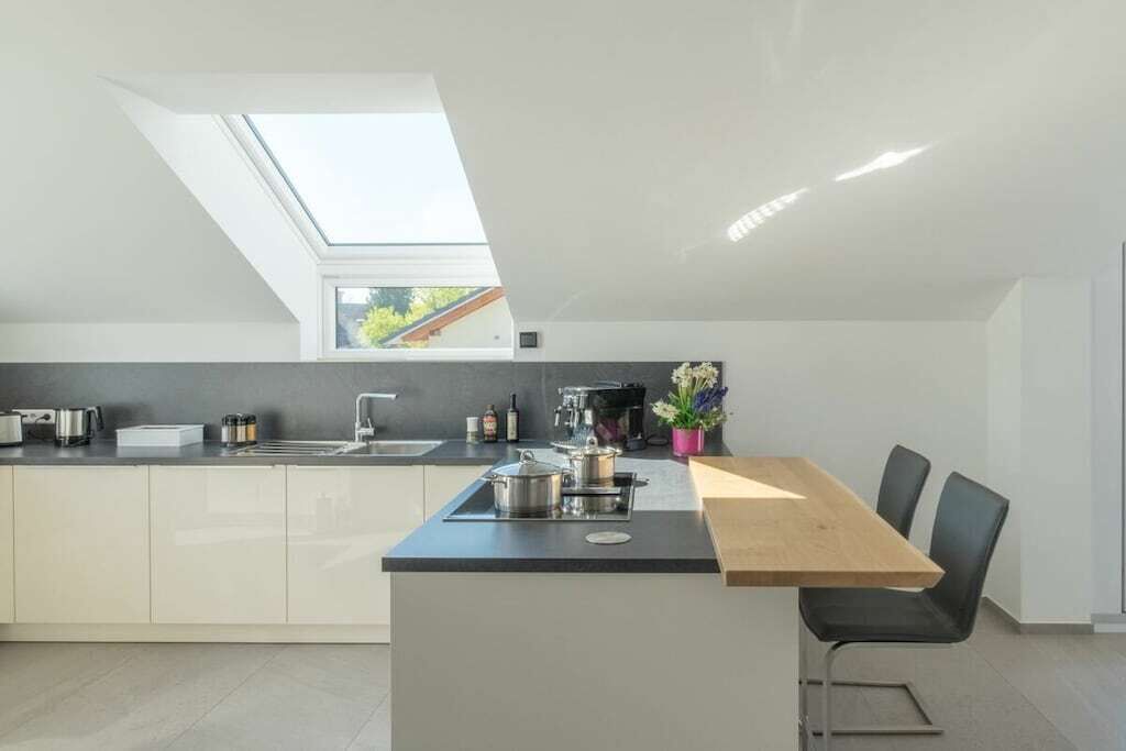 Eine moderne Küche mit Oberlicht, einem Essbereich mit Tisch und Stühlen sowie Blick ins Freie.