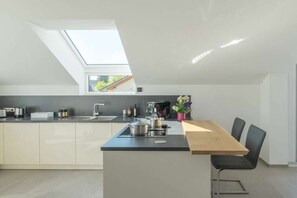 Eine moderne Küche mit Oberlicht, einem Essbereich mit Tisch und Stühlen sowie Blick ins Freie.