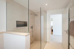 Ein modernes Badezimmer mit Duschkabine aus Glas, integriertem WC und einer sichtbaren Tür zu einem anderen Raum.