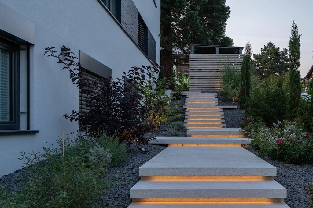 A modern building with a concrete pathway leading to a gated entrance.