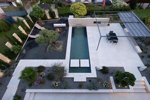 A rooftop pool with a rectangular shape, surrounded by a garden with various plants and a seating area with a table and chairs. - Holiday apartment with 1 bedroom (Überlingen)