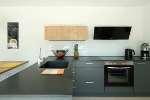 Een moderne keuken met een ingebouwde oven, een koffiezetapparaat en een schaal met fruit.