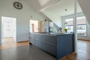 A modern kitchen with a large island, built-in appliances, and a view to the outside. - Holiday apartment with 2 bedrooms (Uhldingen-Mühlhofen)