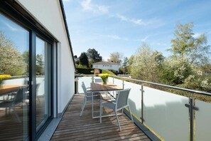 Ein Balkon mit Holzboden, einem Tisch und Stühlen sowie Blick auf die Umgebung.