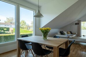Ein Essbereich mit einem Holztisch, schwarzen Stühlen und einer Vase mit gelben Blumen.