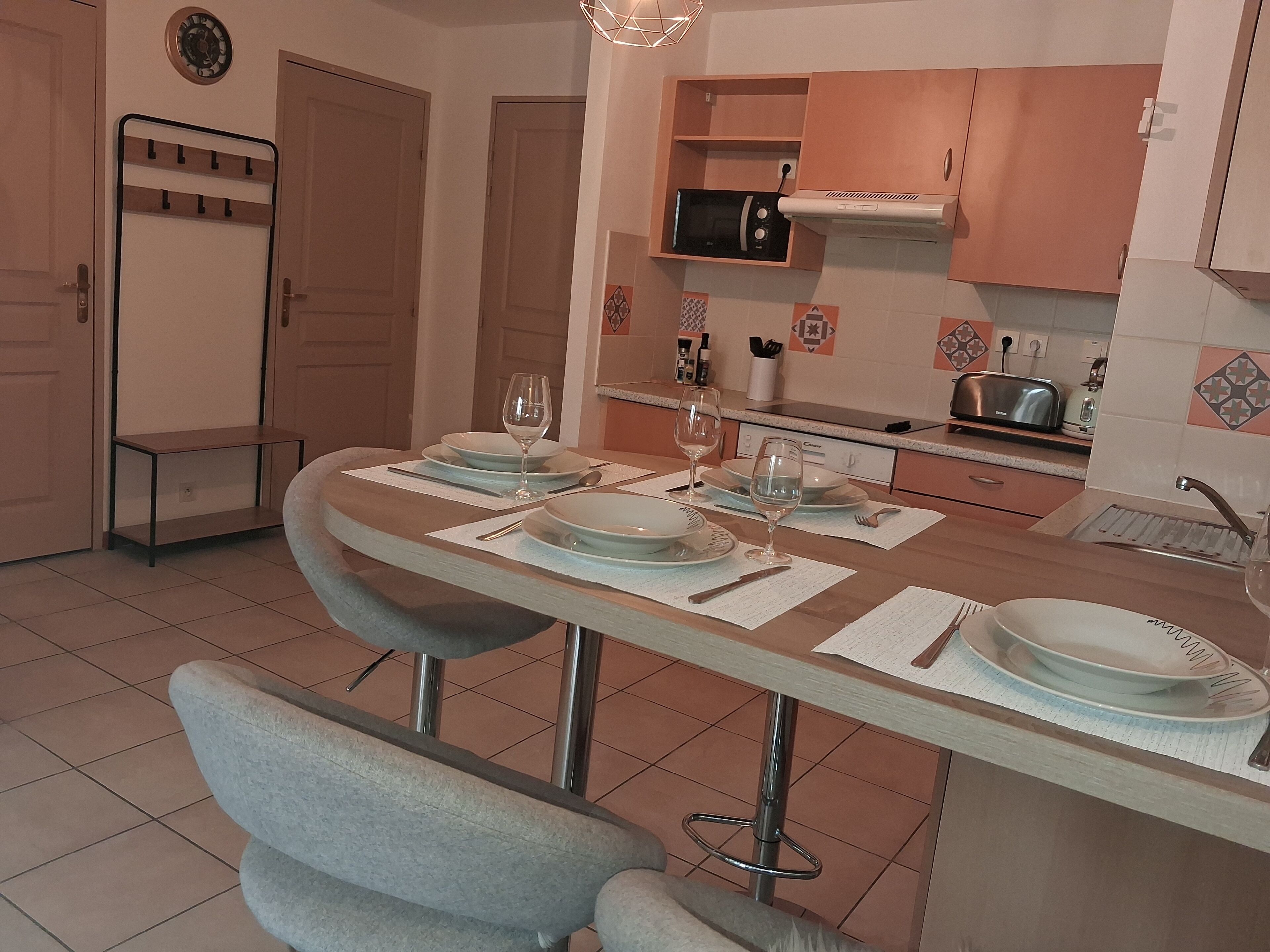 A dining area with a table set for four, a microwave above the counter, and a sink with a faucet.