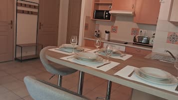 A dining area with a table set for four, a microwave above the counter, and a sink with a faucet.