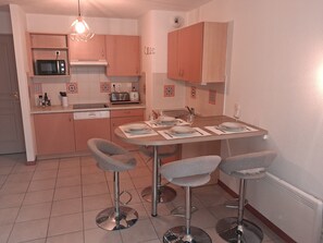 A compact kitchen with a microwave, toaster, and a dining area with two bar stools. - Beautiful apartment located right in the heart of Burgundy (Levernois)