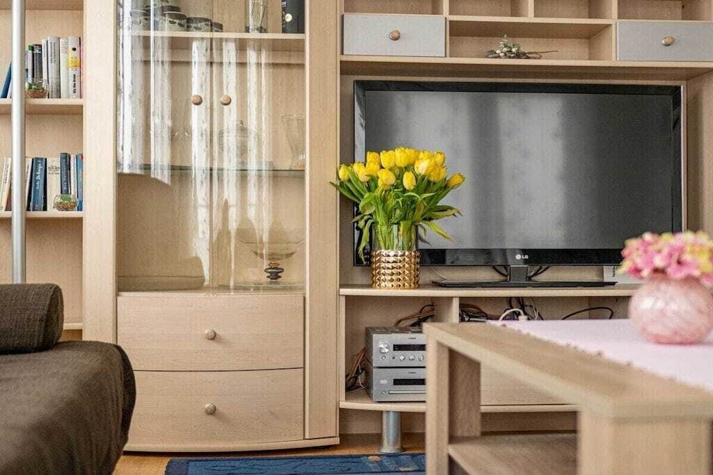 Ein Wohnzimmer mit Flachbildfernseher, Bücherregal, Couchtisch und einer Couch.