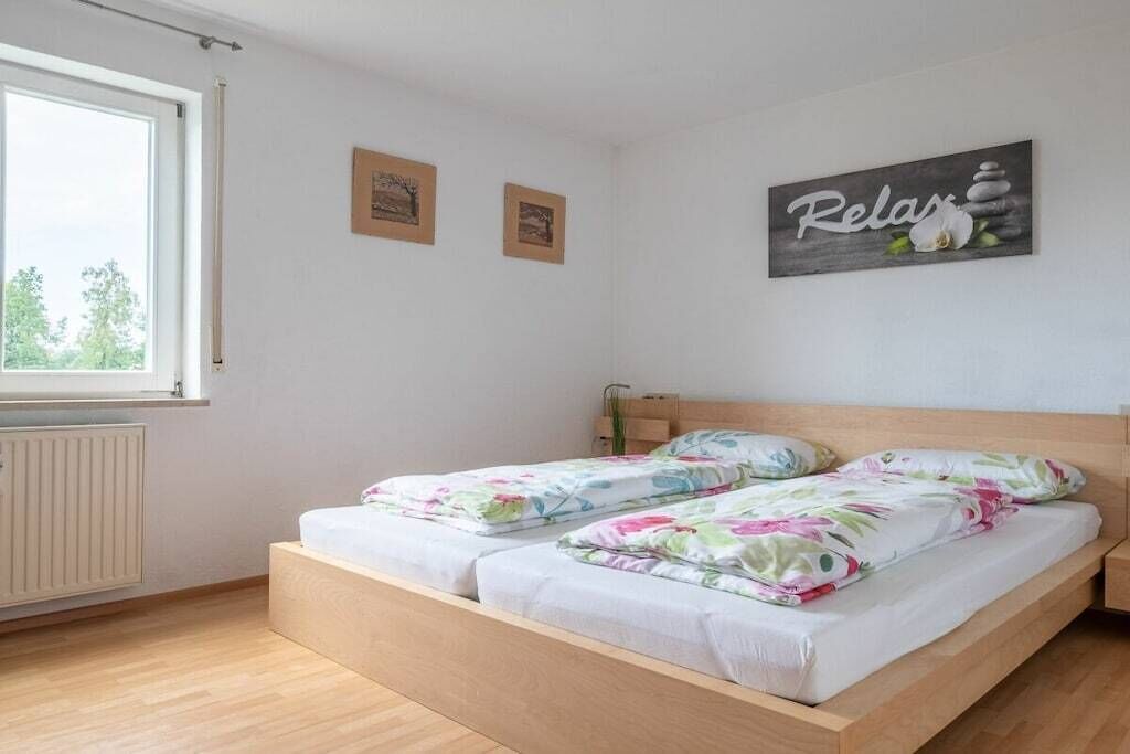 Un dormitorio con dos camas, una ventana y una pared con el letrero 'Relax'.