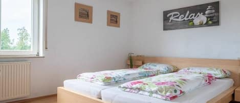Ein Schlafzimmer mit zwei Betten, einem Fenster und einer Wand mit dem Schriftzug 'Relax'.