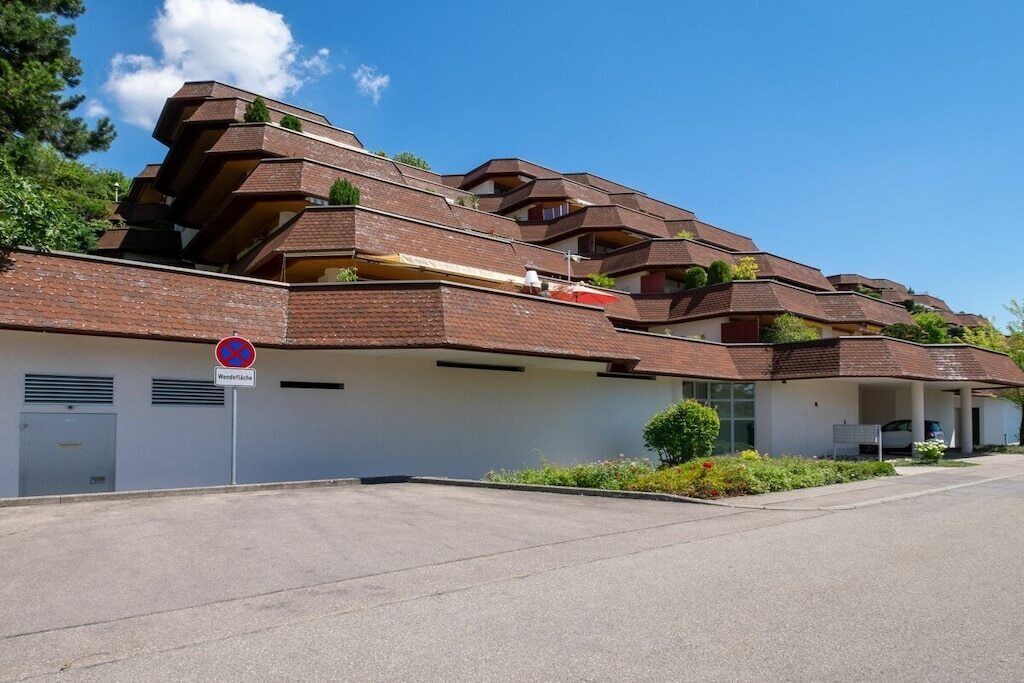 A multi-story residential building with a distinctive architectural style, featuring a series of balconies and a no parking sign.