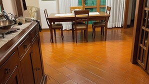 A dining area with a wooden table and chairs, a kitchen counter with a sink, and a tiled floor. - Marisa's Home (Santa Croce sull'Arno)