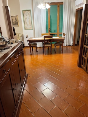 A dining area with a wooden table and chairs, a kitchen counter with a sink, and a tiled floor. - Marisa's Home (Santa Croce sull'Arno)