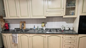 A kitchen with light-colored cabinets, a black stove, and a tiled backsplash. - Marisa's Home (Santa Croce sull'Arno)