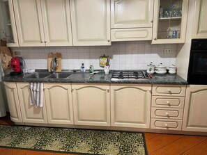 A kitchen with light-colored cabinets, a black stove, and a tiled backsplash. - Marisa's Home (Santa Croce sull'Arno)