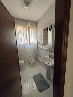 A bathroom with a toilet, bidet, sink, and a mirror above the sink. - Marisa's Home (Santa Croce sull'Arno)