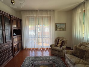 A living room with a wooden cabinet, a patterned rug, a sofa, and a chair. - Marisa's Home (Santa Croce sull'Arno)