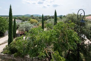 A garden with various trees and shrubs, a stone wall, and a metal fence. - Mas Carpe Diem (sleeps 14) with a pool and game room, ideal for families (Orthoux-Sérignac-Quilhan)