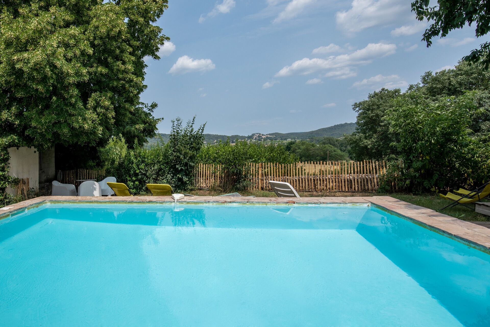 Una piscina con sillones de descanso y vistas al campo.