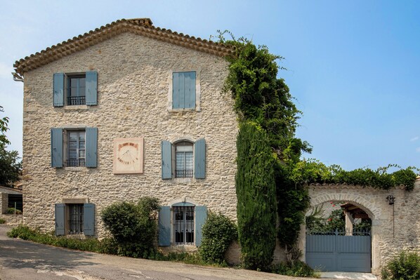 A stone building with multiple windows and shutters, a clock, and a gate. - Vrbo Property (Orthoux-Sérignac-Quilhan)