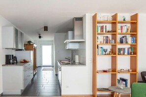 Eine moderne Küche mit weißen Schränken, einer zentralen Kochinsel und einem Bücherregal voller Bücher.