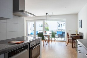 Een moderne keuken met een inbouwoven en een eethoek met een tafel en stoelen.