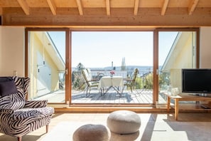 A balcony with a table and chairs, a sofa, a television, and a view of the outdoors. - Holiday apartment with 1 bedroom (Überlingen)