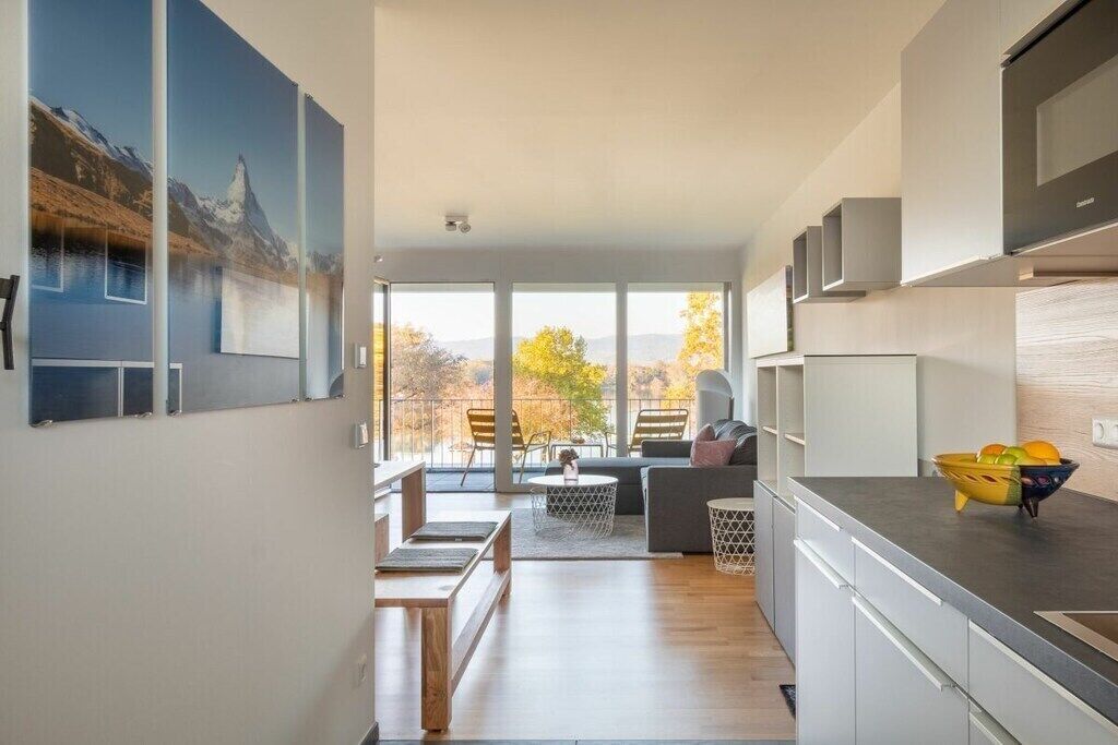 Eine moderne Küche mit Essbereich, großen Fenstern und Blick ins Freie.