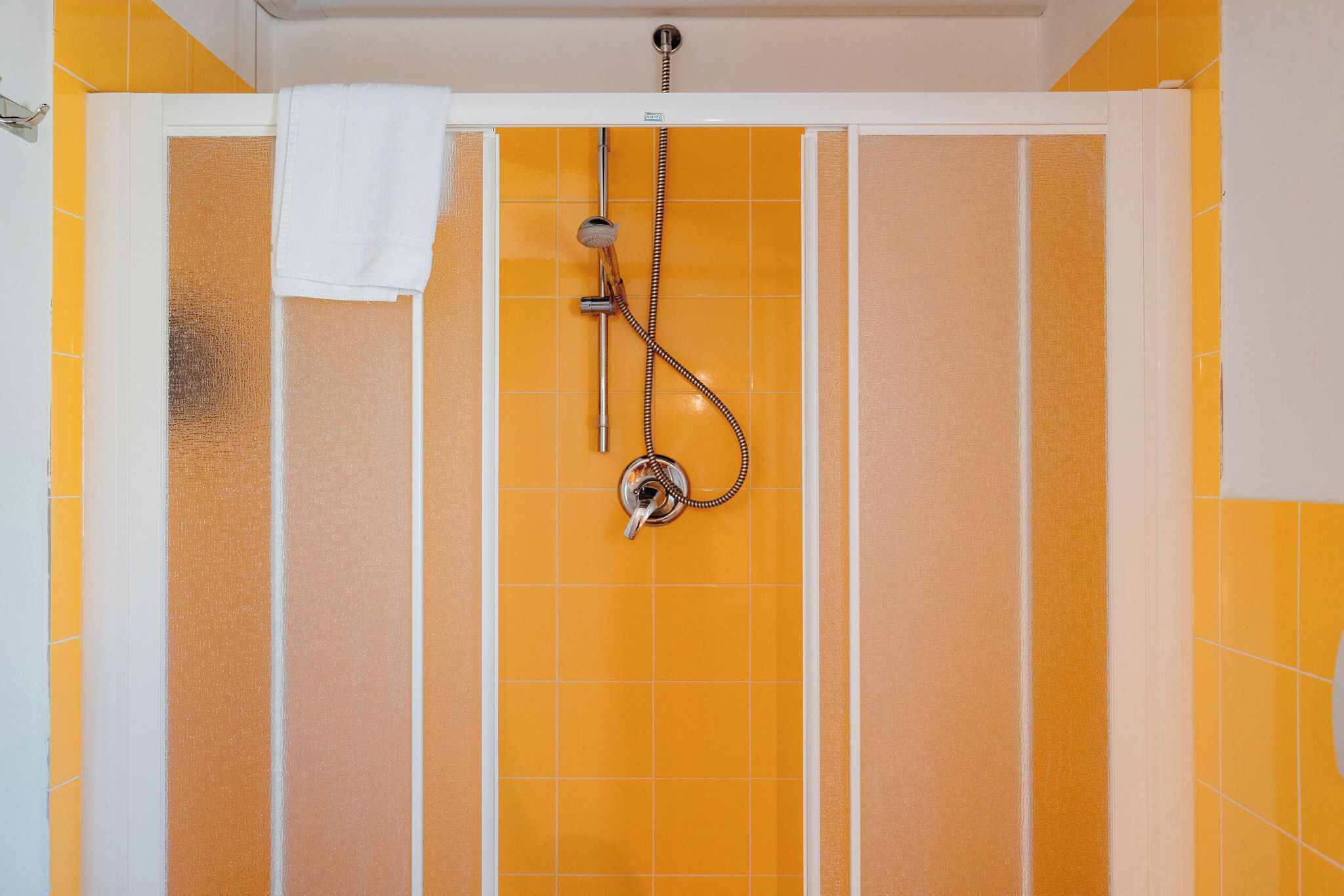 A shower with a handheld showerhead and a wall-mounted faucet.