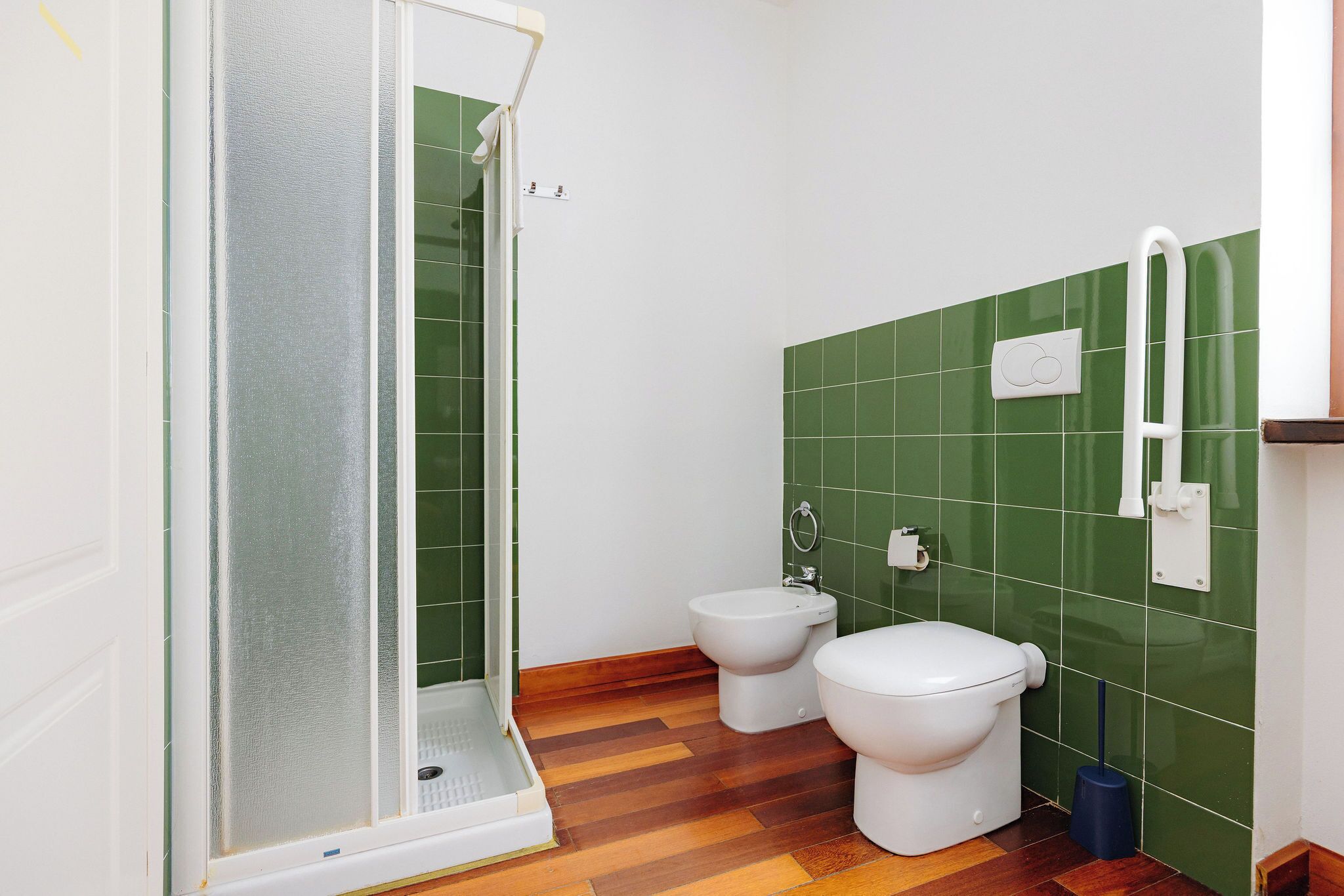 Un baño con ducha, dos inodoros y un bidé.