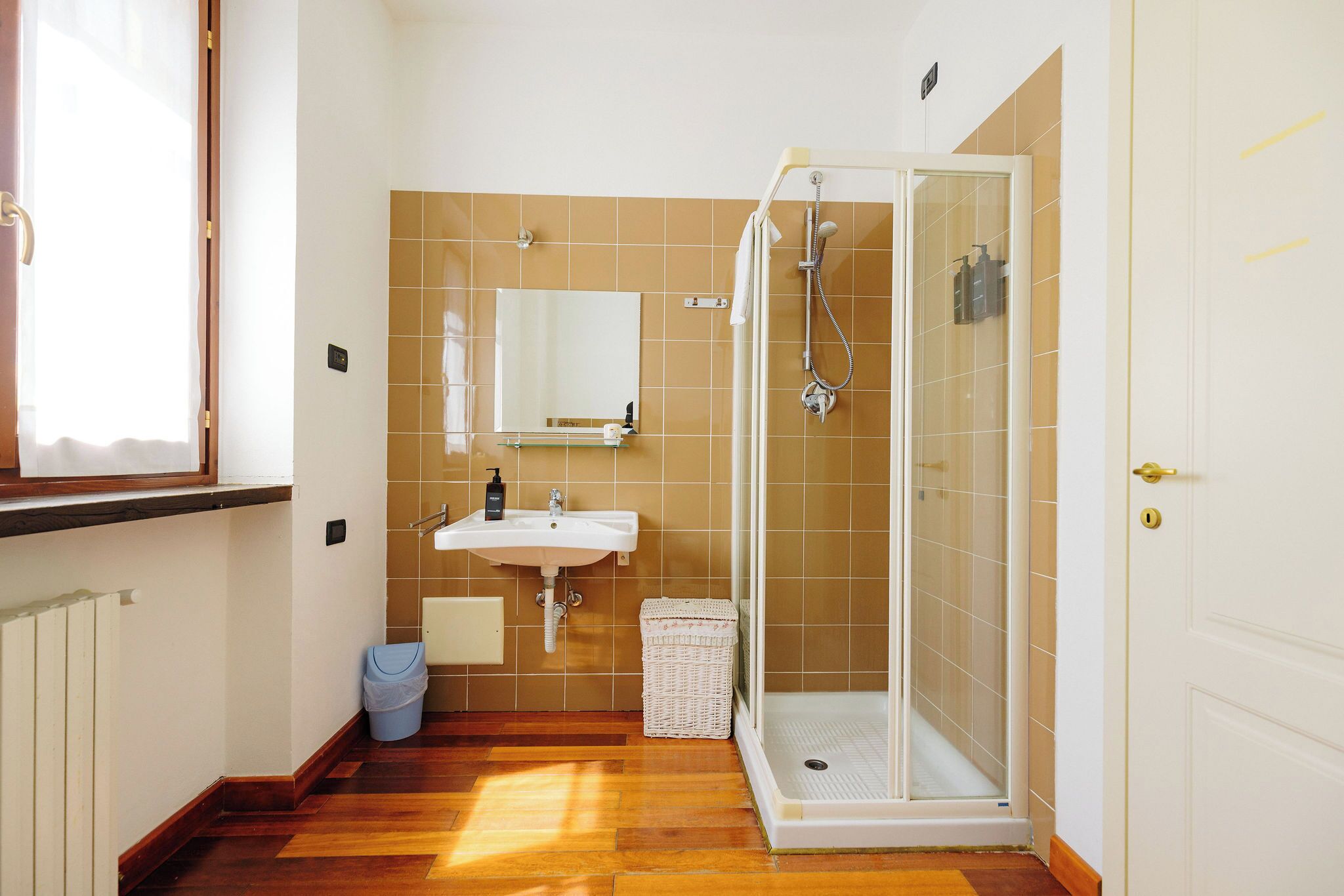 Een badkamer met een douche, wastafel en een raam.